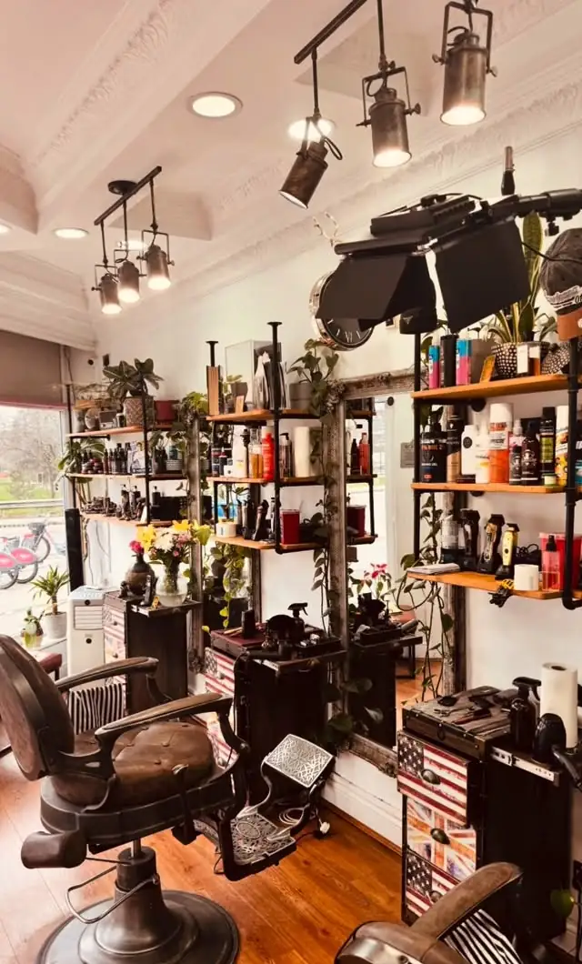 Inside the shop: wooden shelves of products, hanging plants and antique barber chairs
