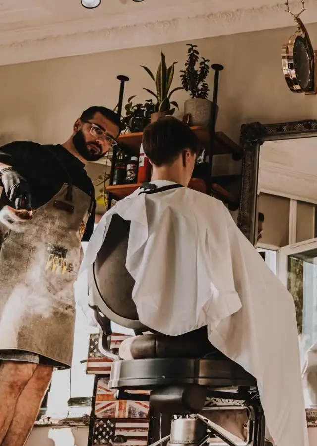A barber works on a client in the window light at URBAN Barbers